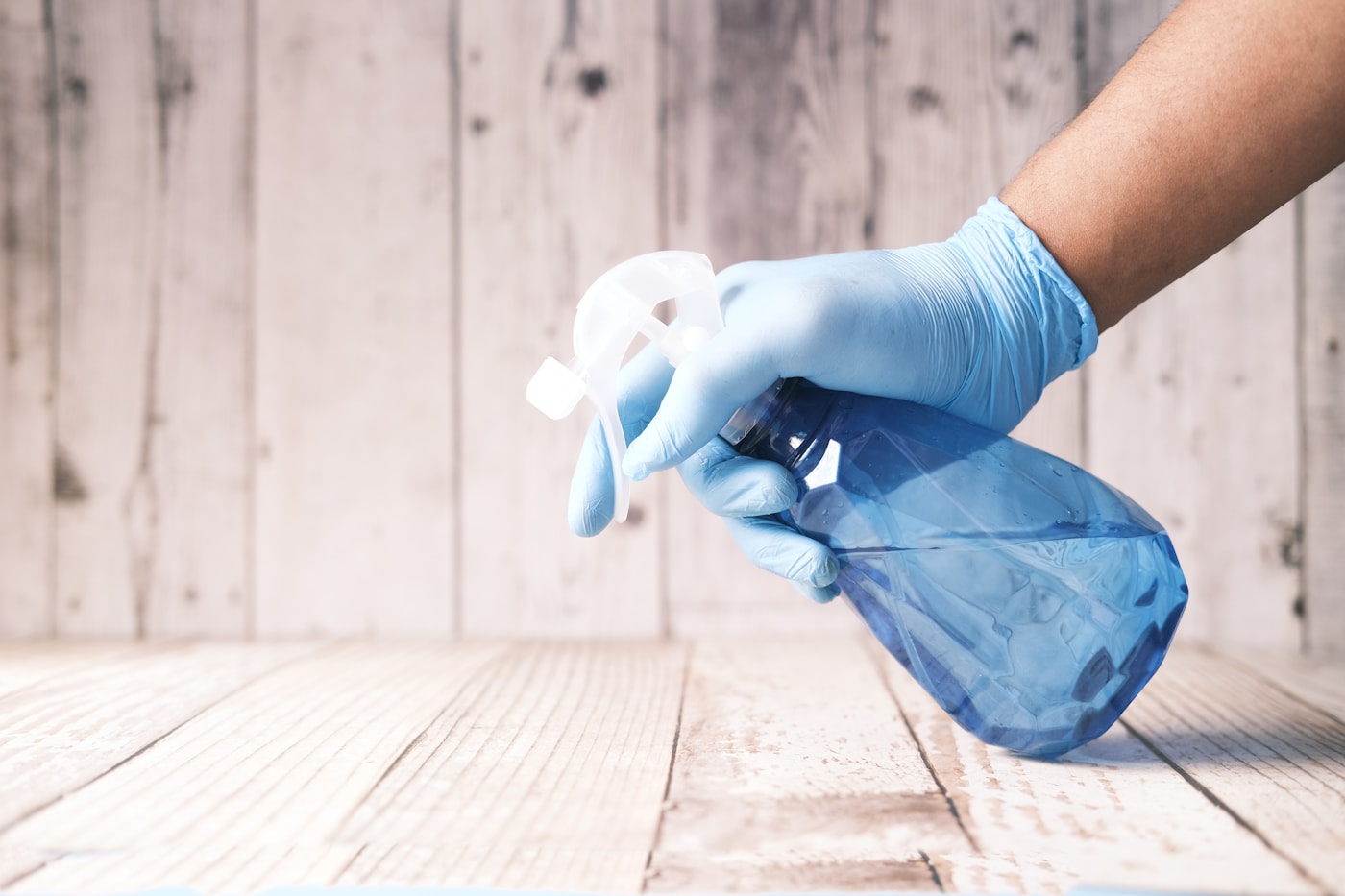A gloved hand holding a professional cleaning spray bottle